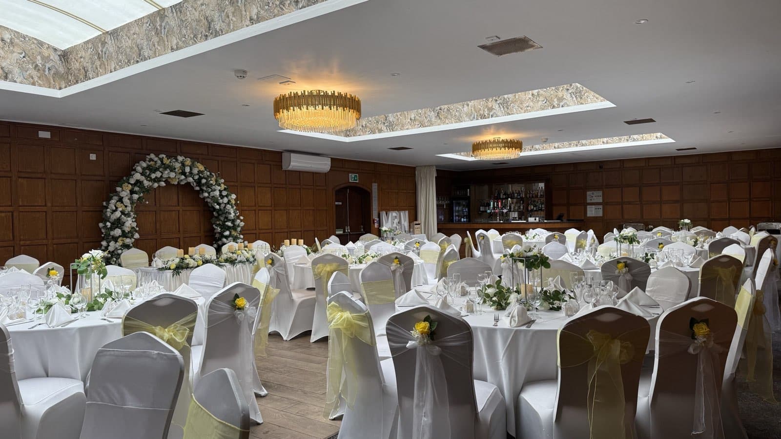 The Malt House set for a wedding breakfast with round tables and a floral arch